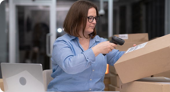 Vista de una mujer revisando entregas en cajas. Al fondo hay más cajas.